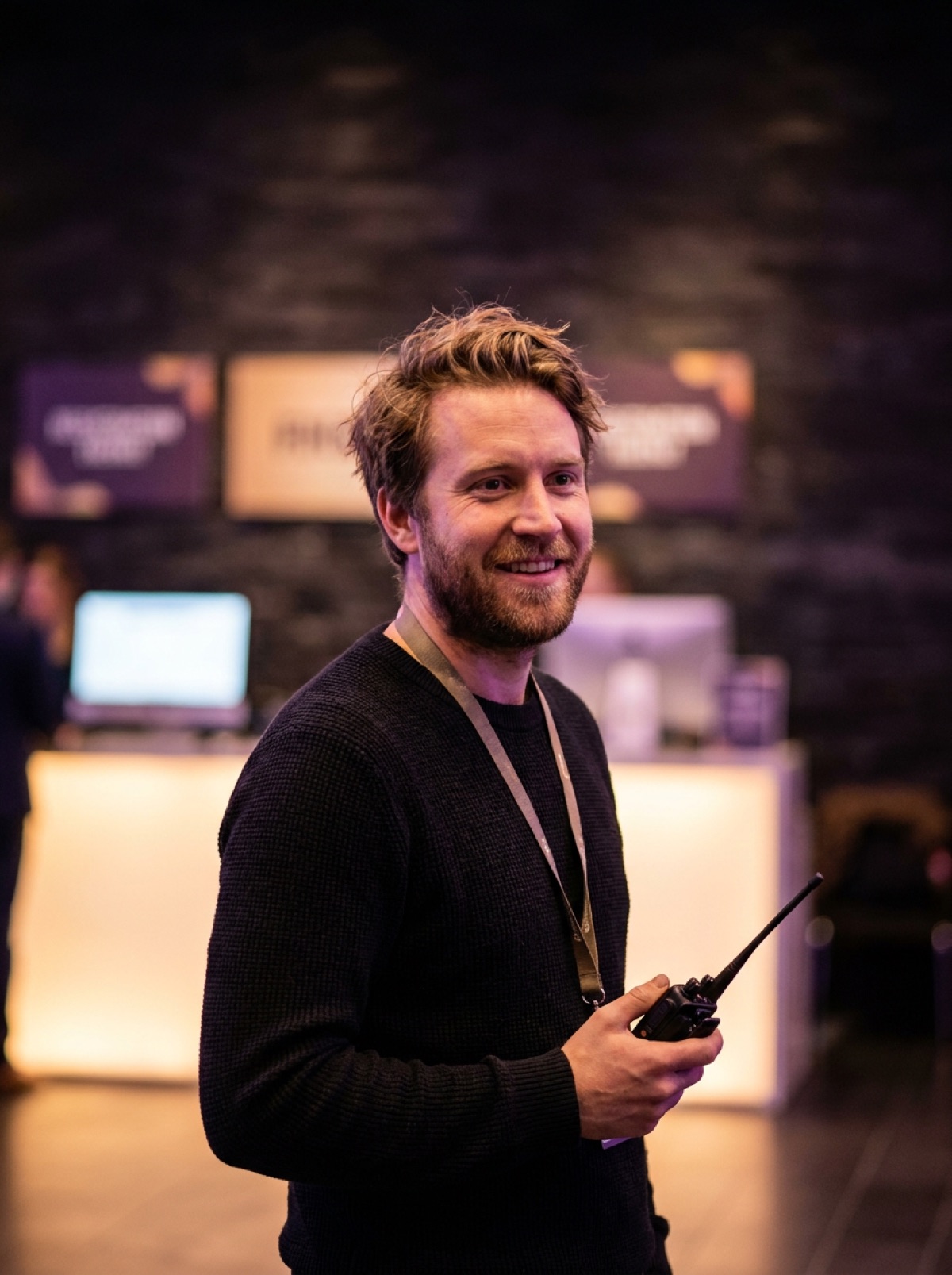 Sam Lindqvist in a lobby by the registration desk, holding a radio